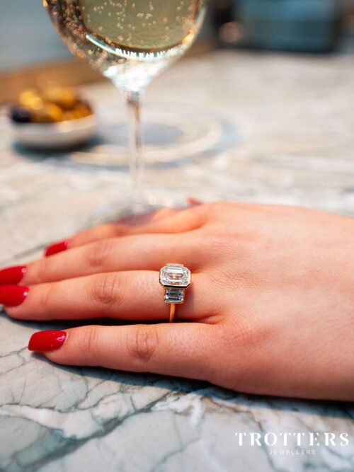 Trotters 18ct Yellow Gold 3ct Emerald Cut Lab Grown Diamond Ring With Baguette Shoulders Bezel / Rubover Set